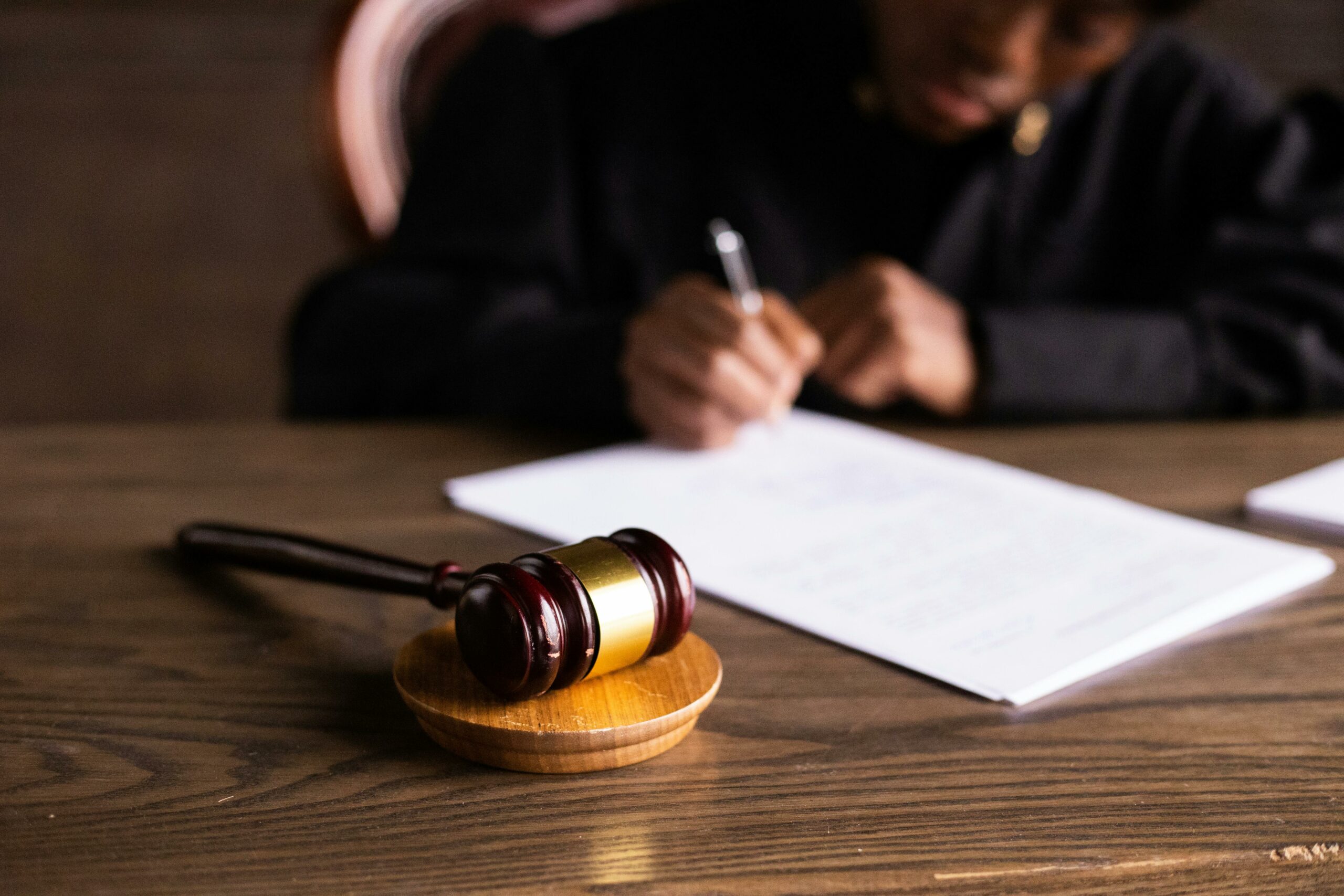 Judge writes on paper with a hammer next to it.