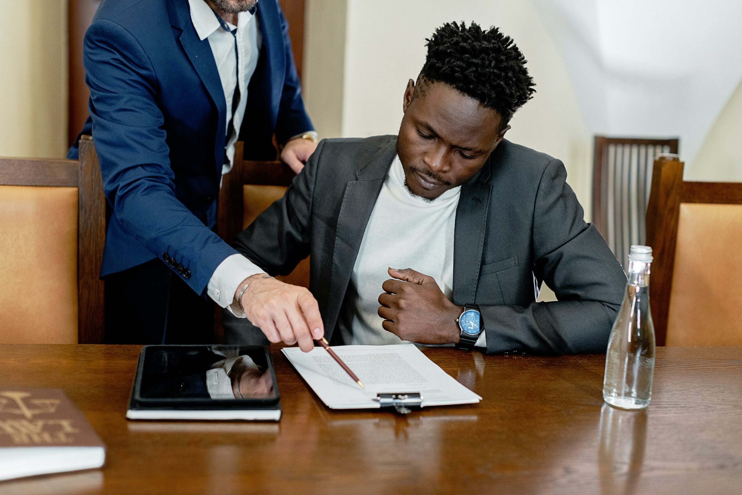 Two men at a table discussing a document.